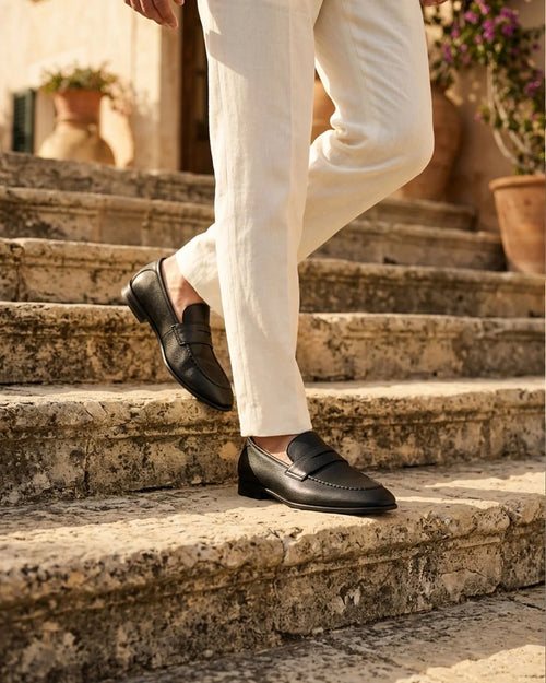 Black penny loafer worn on stone steps